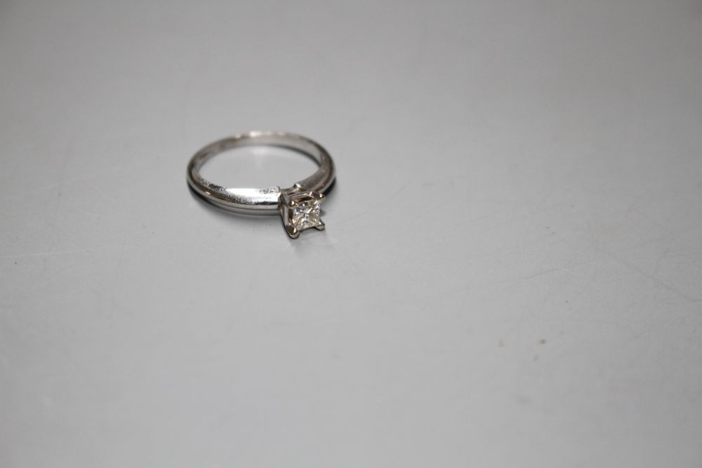 A modern 14k white metal and princess cut solitaire diamond ring, the stone weighing 0.25cts,